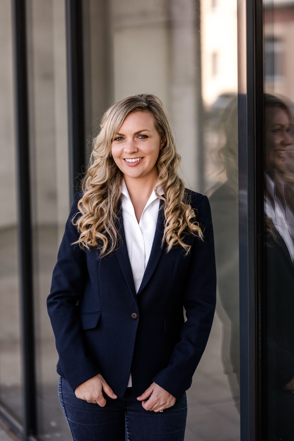 Susanne Weller, Immobilienmaklerin, im marineblauen Blazer vor einer Glasfassade